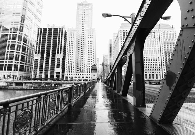 A steel truss bridge over a city river, framed by high-rise buildings on either side