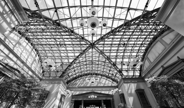 Looking up at an interlocking grid of steel roof trusses supporting a glass skylight